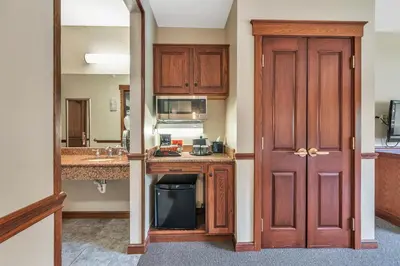 a kitchen with wooden cabinets and a sink and a door at The Inn at Ohio Northern University in Ada