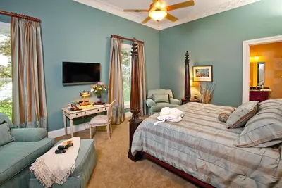 a bedroom with blue walls and a bed and a couch at Riverside Inn Bed and Breakfast, Wedding Venue & Events in Warsaw