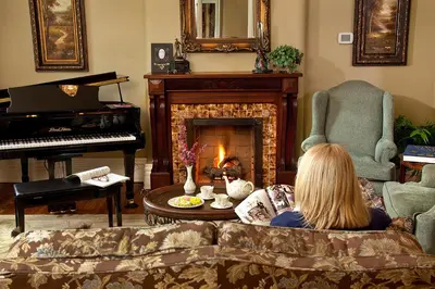 a woman sitting on a couch in a living room with a piano at Riverside Inn Bed and Breakfast, Wedding Venue & Events in Warsaw