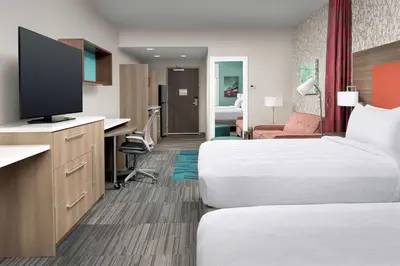a hotel room with two beds and a flat screen tv at Home2 Suites By Hilton Columbus Polaris in Columbus