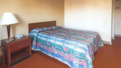 a bedroom with a bed and a lamp and a nightstand at Red Horse Motel Dayton Moraine in Dayton