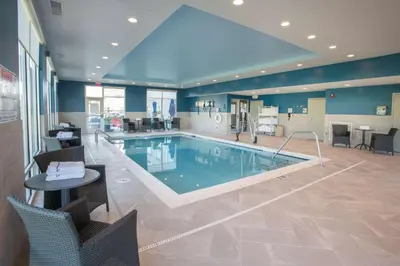 a large swimming pool with chairs and a table in a building at Hampton Inn Richwood Cincinnati South, KY in Richwood