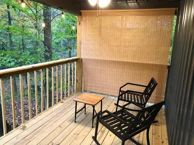 a porch with two chairs and a table on it at Avenwood Cabins in Logan