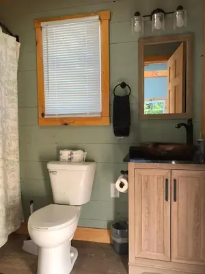 a bathroom with a toilet and a sink and a mirror at Avenwood Cabins in Logan