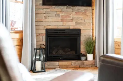 a brick fireplace with a television above it at Family Friendly ~ Hocking Hills Cabin ~ Close to Caves, w/Wifi in South Bloomingville