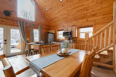 a dining room and kitchen in a log cabin at Family Friendly ~ Hocking Hills Cabin ~ Close to Caves, w/Wifi in South Bloomingville