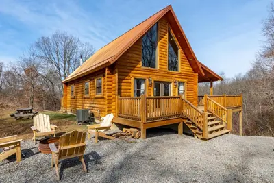 a log cabin with a porch and two chairs at Family Friendly ~ Hocking Hills Cabin ~ Close to Caves, w/Wifi in South Bloomingville