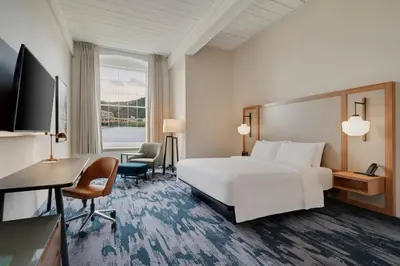 a hotel room with a white bed and a desk at Fairfield Inn & Suites Madison Historic Eagle Cotton Mill in Madison