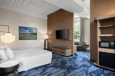 a hotel room with a bed and a flat screen tv at Fairfield Inn & Suites Madison Historic Eagle Cotton Mill in Madison