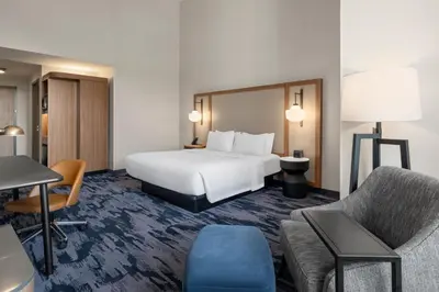 a hotel room with a white bed and a chair at Fairfield Inn & Suites Madison Historic Eagle Cotton Mill in Madison