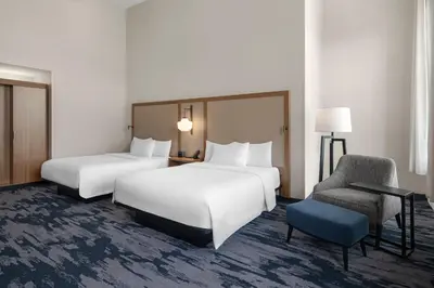 a hotel room with two beds and a chair at Fairfield Inn & Suites Madison Historic Eagle Cotton Mill in Madison