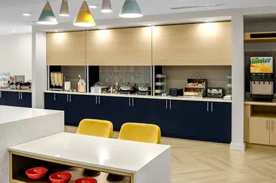 a kitchen with blue cabinets and yellow chairs at TownePlace Suites by Marriott Ironton in Ironton