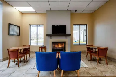 a waiting room with a fireplace and tables and chairs at Days Inn by Wyndham Perrysburg Toledo in Perrysburg
