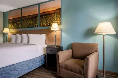 a hotel room with a bed and a chair at Days Inn by Wyndham Perrysburg Toledo in Perrysburg