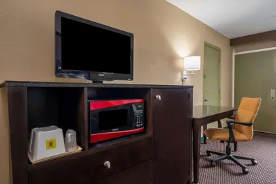 a hotel room with a television and a desk with a chair at Super 8 by Wyndham Perrysburg-Toledo in Perrysburg