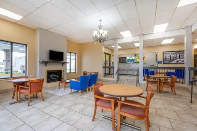 a dining room with tables and chairs and a fireplace at Super 8 by Wyndham Perrysburg-Toledo in Perrysburg