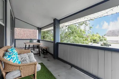 a screened porch with a wicker chair and a table at Chic 2BR near DT, 8 min walk to Park&Conservatory in Columbus