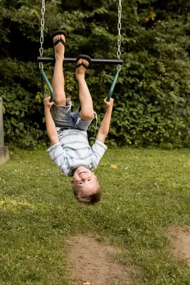 a young child is hanging on a swing at Canadian Hemlock . Trailside Lodging in Millersburg