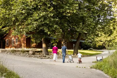 a family walking down a road with their child on aicycle at Canadian Hemlock . Trailside Lodging in Millersburg