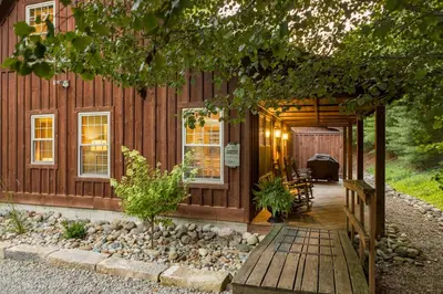 a cabin with a porch and a wooden walkway at Canadian Hemlock . Trailside Lodging in Millersburg