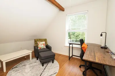 a living room with a chair and a desk and a window at Home STEPS from Oberlin in Oberlin