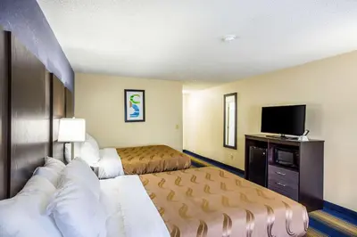 a hotel room with two beds and a flat screen tv at Quality Inn Charleston South in Charleston