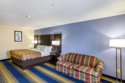 a hotel room with a bed and a chair at Quality Inn Charleston South in Charleston