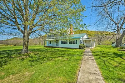 a house on a grassy field with a tree at Renovated KY Farmhouse Retreat with Pasture Views! in Wallingford