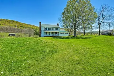 a white house on a green field with a tree at Renovated KY Farmhouse Retreat with Pasture Views! in Wallingford