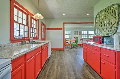 a large kitchen with red cabinets and a table at Renovated KY Farmhouse Retreat with Pasture Views! in Wallingford