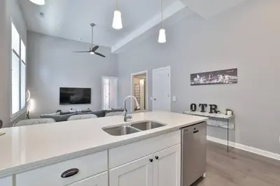 a white kitchen with a sink and a living room at **NEW mOdernLUX best OTR condo *Park ONsite** in Cincinnati