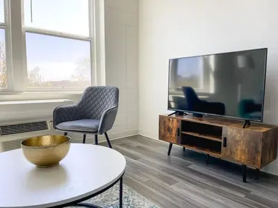 a living room with a tv and two chairs and a table at Sleepover Downtown Cincinnati 1BD 1BA Apartments in Cincinnati