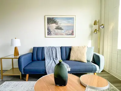 a living room with a blue couch and a table at Sleepover Downtown Cincinnati 1BD 1BA Apartments in Cincinnati