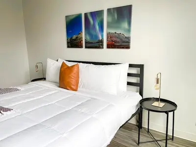 a bedroom with a white bed with three paintings on the wall at Sleepover Downtown Cincinnati 1BD 1BA Apartments in Cincinnati