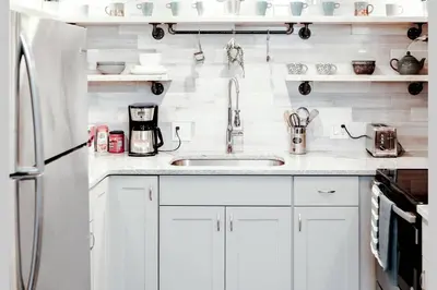a white kitchen with a sink and a refrigerator at Newly Renovated(6A) OSU/ExpoCenter Near EVERYTHING! in Columbus