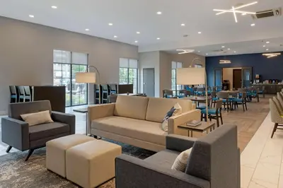 a living room with couches and chairs and a restaurant at MainStay Suites Cincinnati University - Uptown in Cincinnati