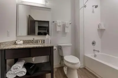 a white bathroom with a toilet and a sink and a tub at MainStay Suites Cincinnati University - Uptown in Cincinnati