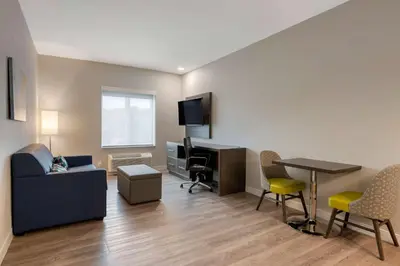 a living room with a couch and a table and chairs at MainStay Suites Cincinnati University - Uptown in Cincinnati