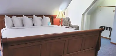 a bedroom with a large bed with a lamp and a chair at Berlin Heritage Inn in Berlin