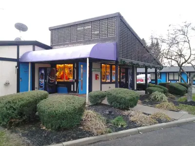 a store front with a purple awning and bushes at Xenia Country Inn in Xenia