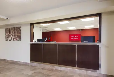 an empty lobby with a waiting area with a red sign on the wall at Red Roof Inn Lawrenceburg in Lawrenceburg
