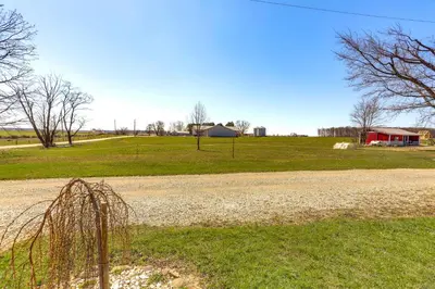 a dirt road next to a field with a house at Quiet Shiloh Retreat with Spacious Yard and Fireplace! in Shiloh
