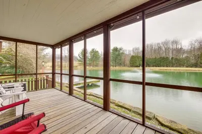 a screened in porch with a view of a lake at Quaint Winesburg Cottage with Porch and Pond! in Dundee