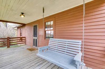 a swinging bench on a porch of a house at Quaint Winesburg Cottage with Porch and Pond! in Dundee