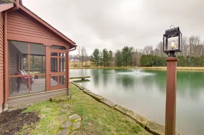 a house with a light pole next to a lake at Quaint Winesburg Cottage with Porch and Pond! in Dundee
