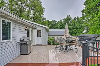 a deck with a table and chairs and an umbrella at Millersburg Home with Covered Porch and Fire Pit! in Millersburg