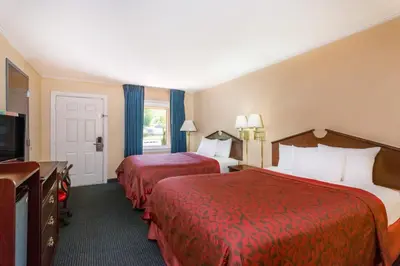 a hotel room with two beds and a flat screen tv at The Inn At Plantation in Weston