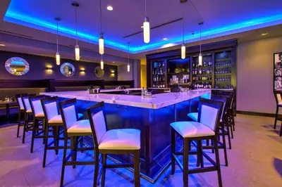 a bar in a restaurant with blue lighting at Hilton Garden Inn Columbus Easton, Oh in Columbus