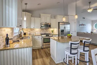 a kitchen with white cabinets and a island with bar stools at Port Clinton Home with Lake Views! in Port Clinton