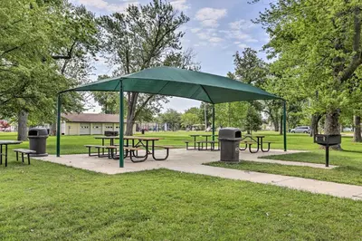 a group of picnic tables and a green umbrella in a park at Port Clinton Home with Lake Views! in Port Clinton